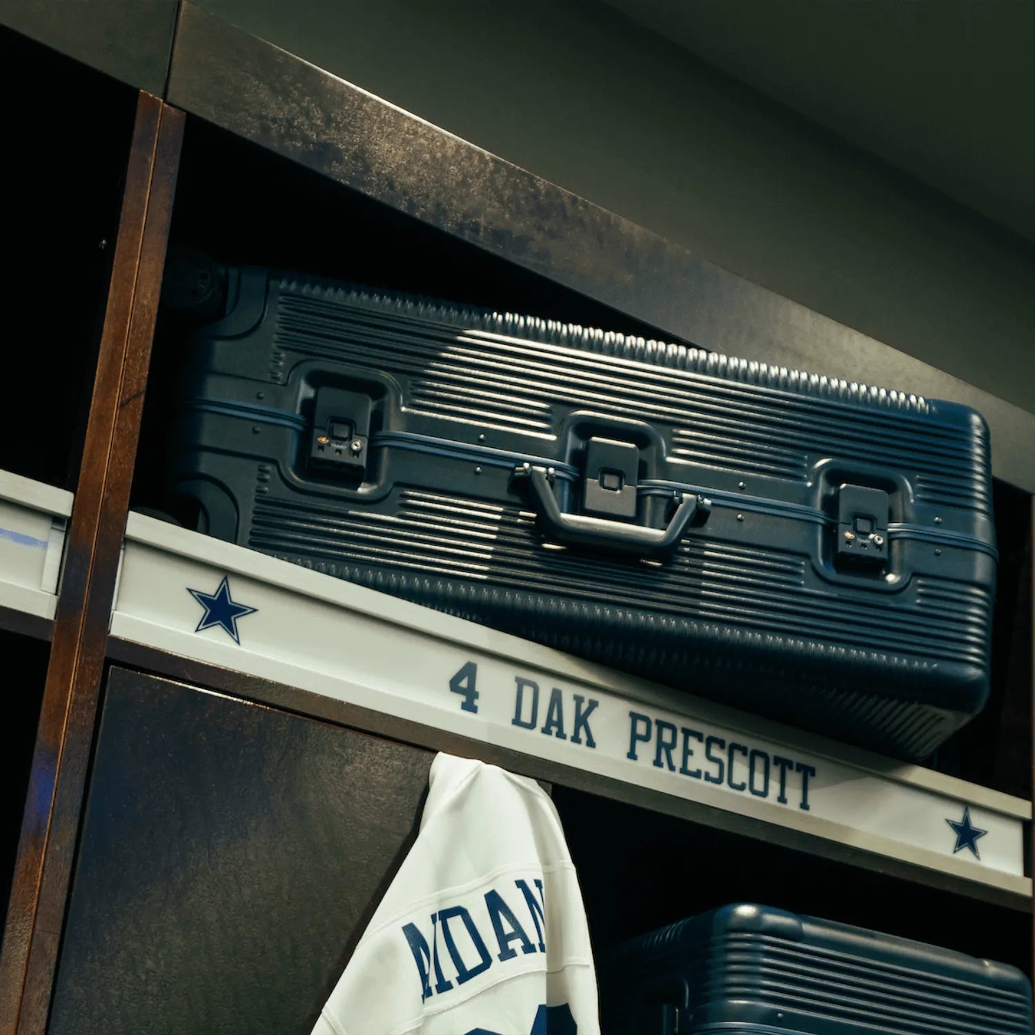 Blue suitcase on a shelf in a locker labeled with Dak Prescott's name.