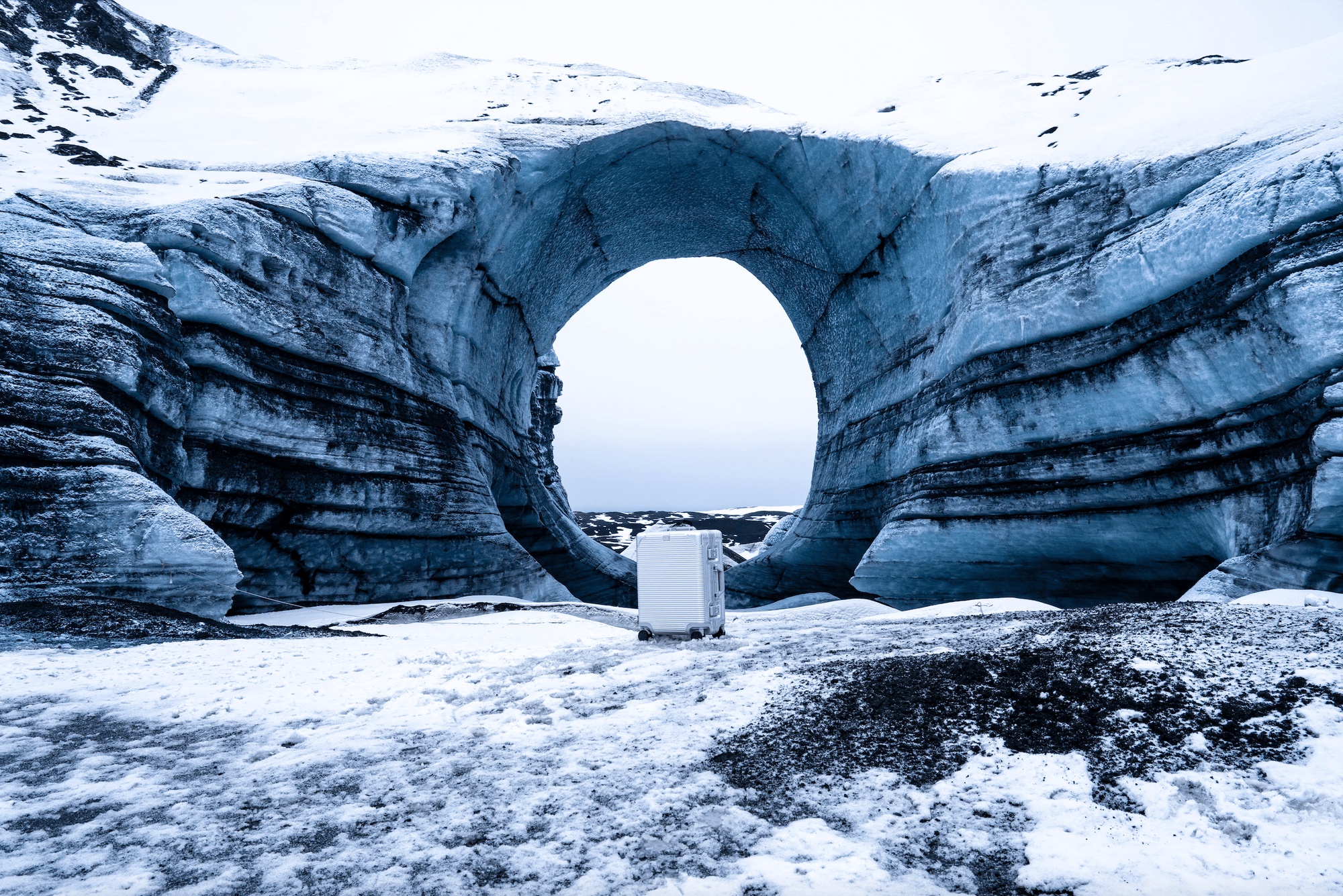 Majestic ice arch formation in a snow-covered landscape with a white object in front.